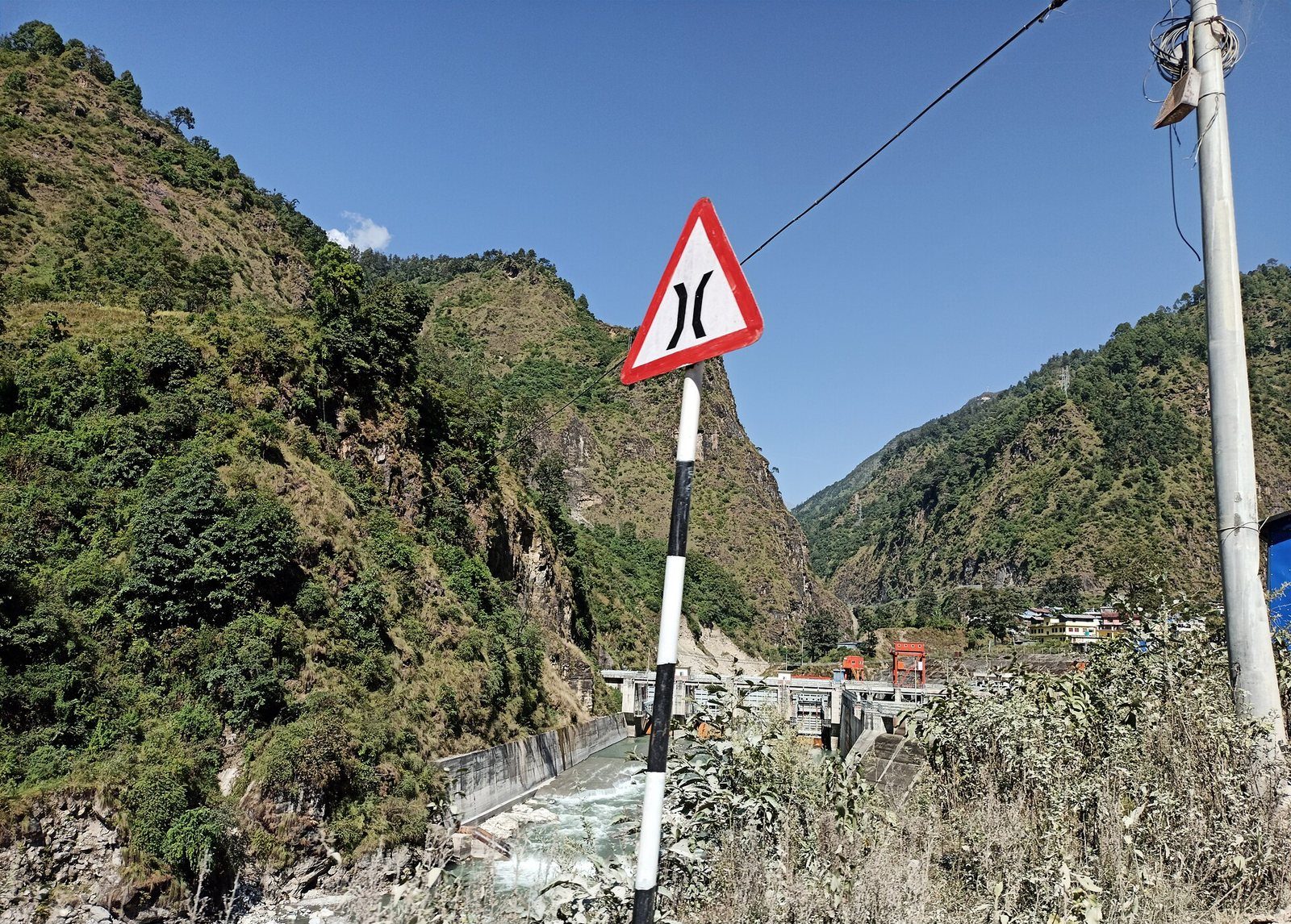 A dam structure on the Bhote Koshi River in Sindhupalchok District, Nepal, surrounded by steep hillsides.