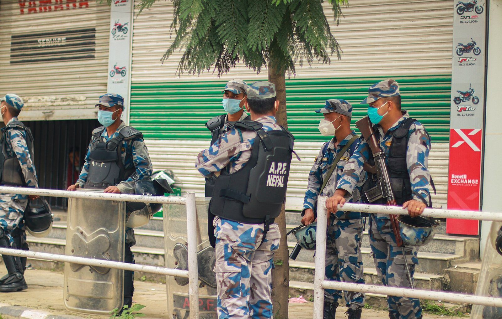 Armed Police Force Nepal officers in camouflage uniform and face masks stand on duty beside a street barrier.