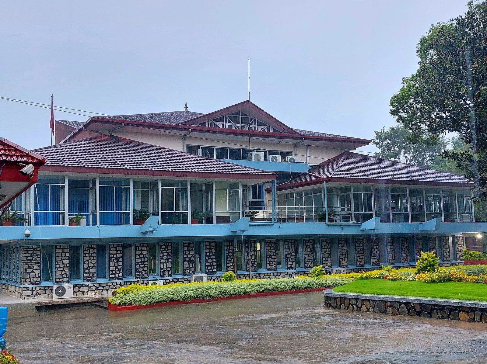 The Nepal Rastra Bank building in Pokhara, a multi-story structure with stone walls and glass windows, photographed in daylight.