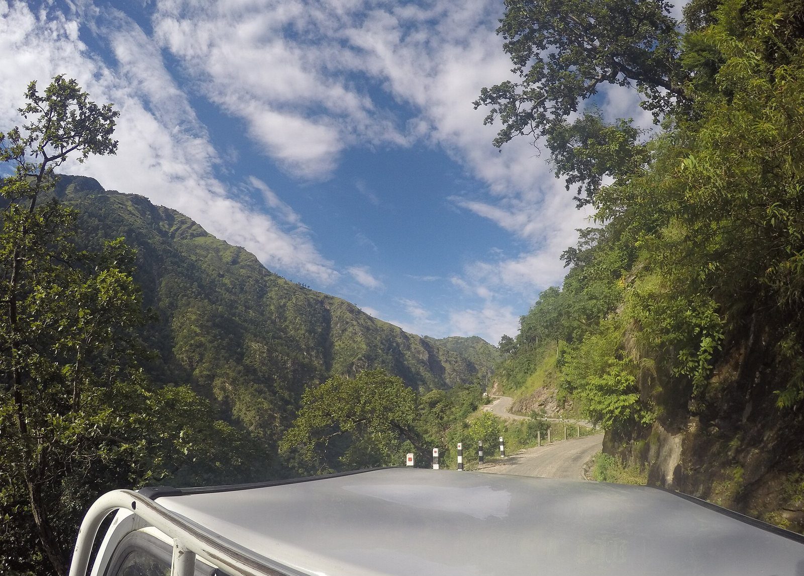 A paved mountain highway winding through steep forested hills, identified as the Karnali Highway near Kalikot, Nepal.