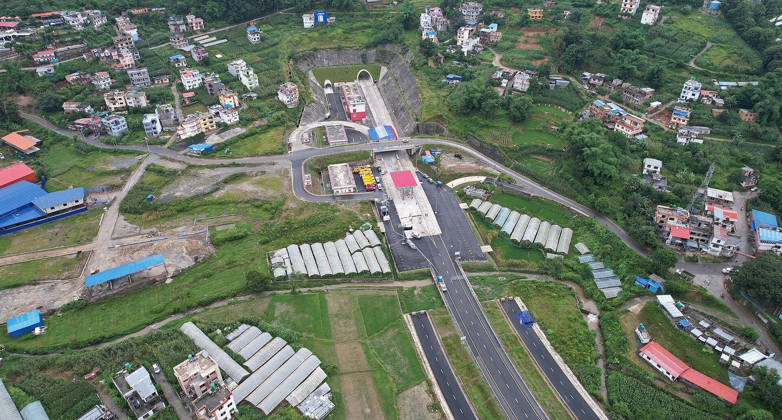 The entrance of the Nagdhunga highway tunnel on the Tribhuvan Highway at the edge of Kathmandu Valley, with hills and buildings in the background.
