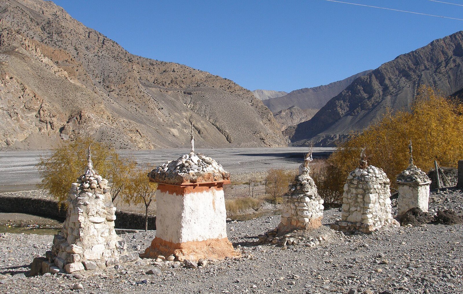 A narrow road winds through the arid Kali Gandaki Valley in Mustang District, Nepal, flanked by steep mountains.