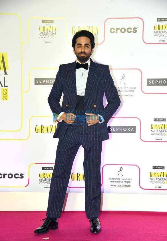 Ayushmann Khurrana poses in a pinstriped suit and bow tie on a red carpet at the Grazia Millennial Awards 2022.