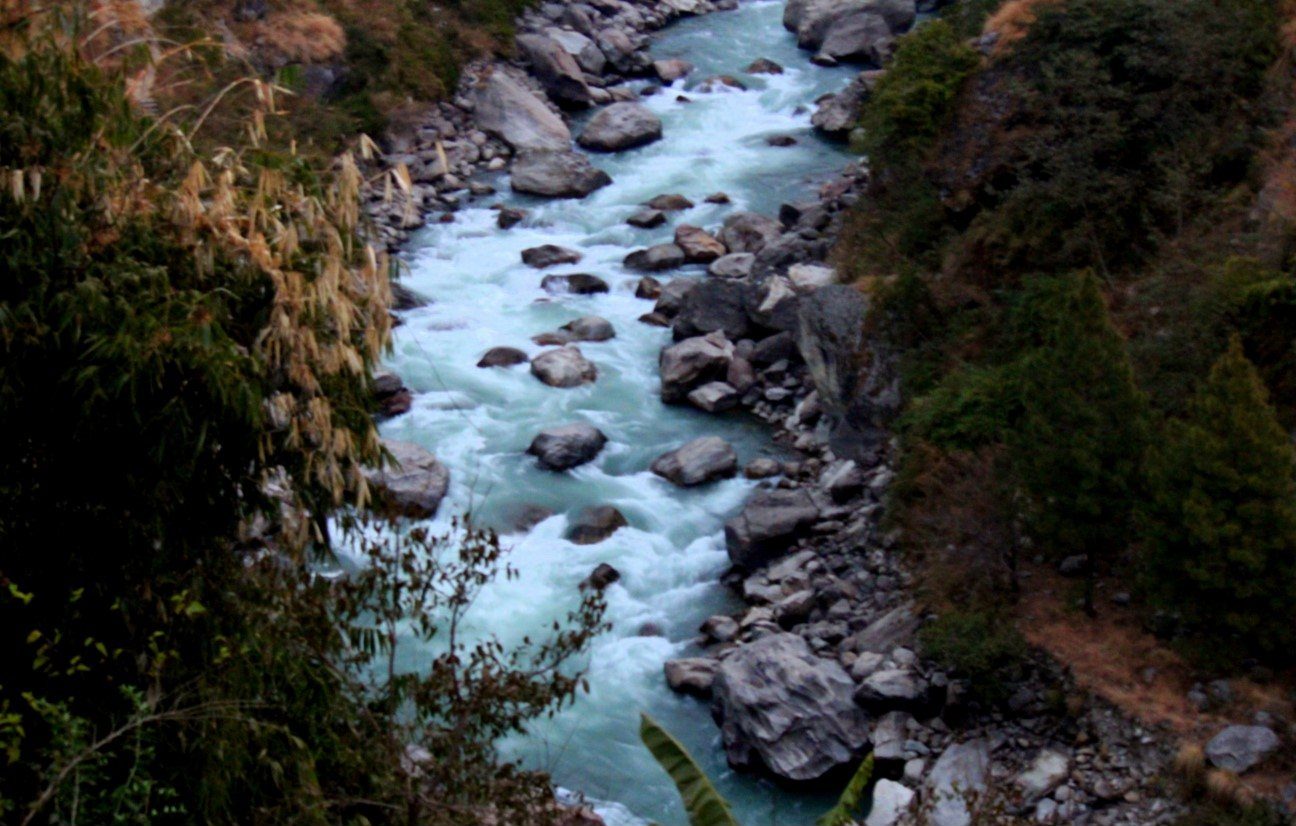 A view of the grey-green Trisuli River flowing through a rocky valley in Rasuwa District, Nepal.